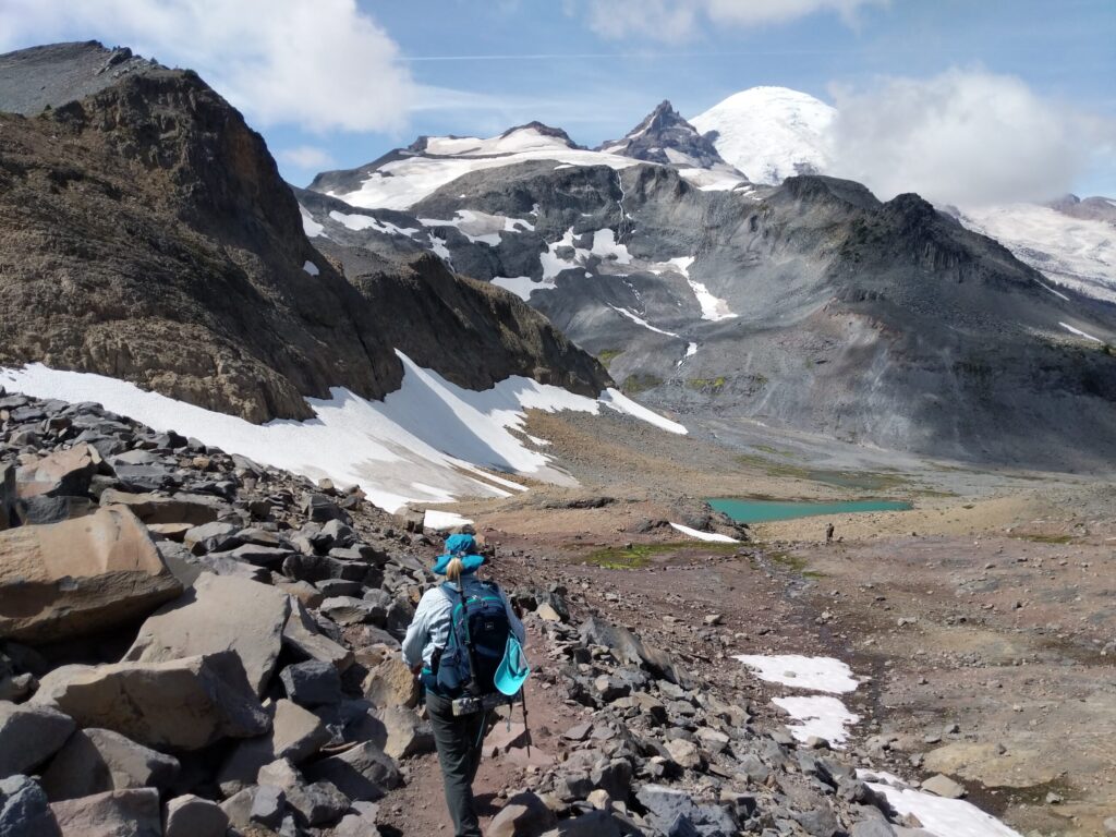 Hiker near Panhandle Gap with view of Mt Rainier on the Wonderland Trail.
